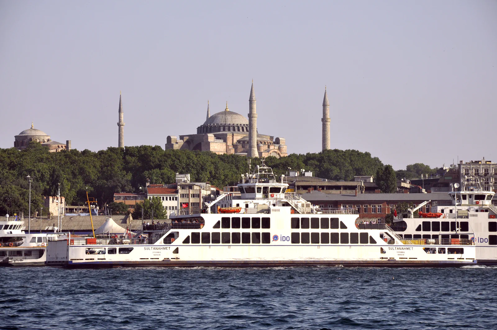 A ferry crossing the Bosphorus with Hagia Sophia and Istanbul's old city skyline behind it