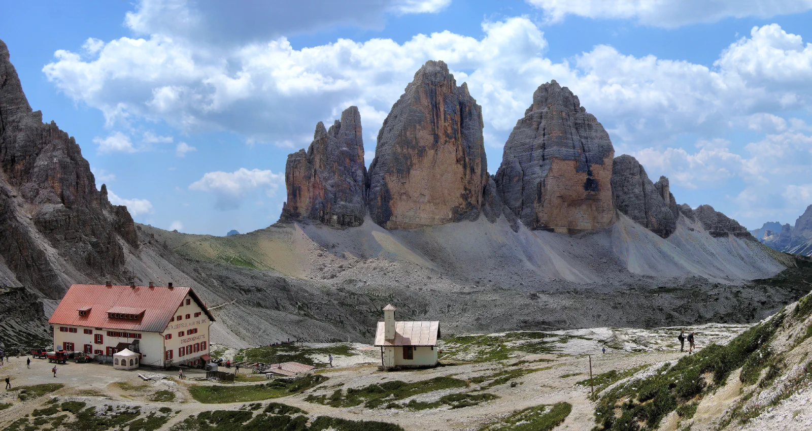 A wide panorama of Tre Cime di Lavaredo and the mountain hut beneath the rocky towers