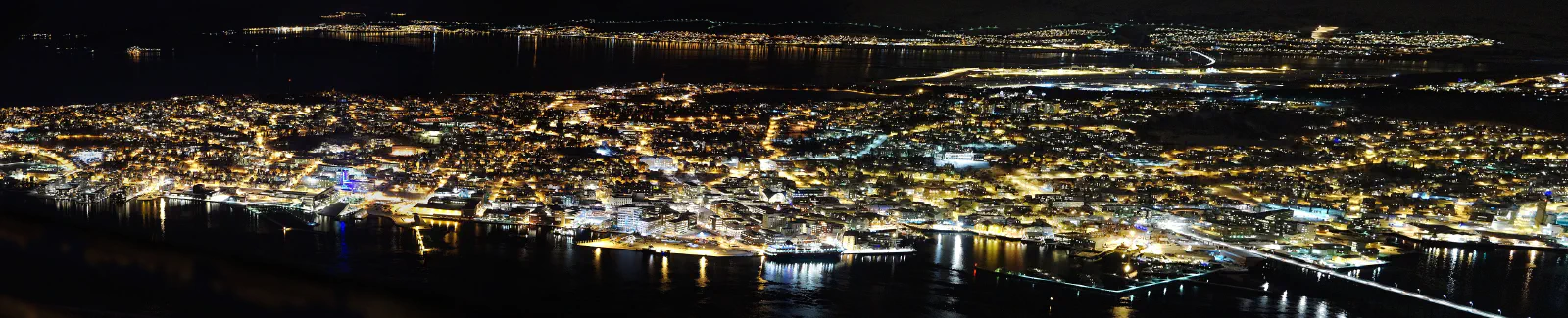 A winter night panorama over Tromso, with city lights stretching along the fjord